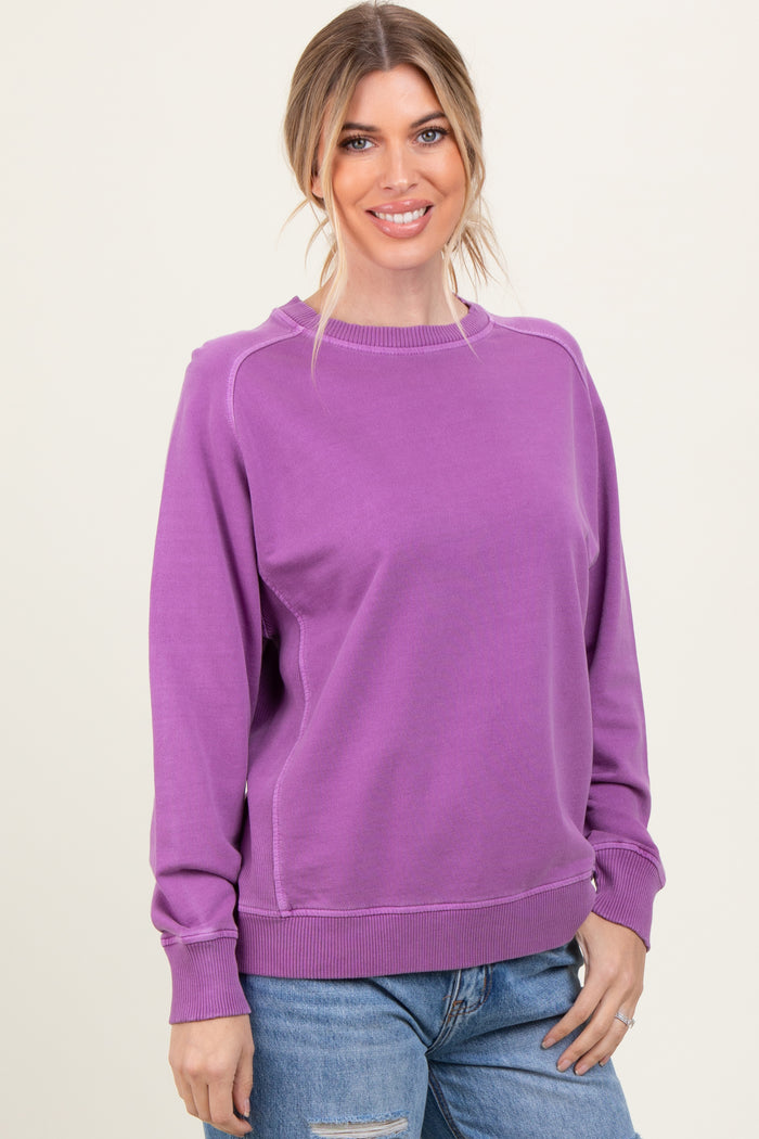 woman wearing a purple long sleeve sweatshirt with a relaxed fit and rounded neckline, smiling at the camera