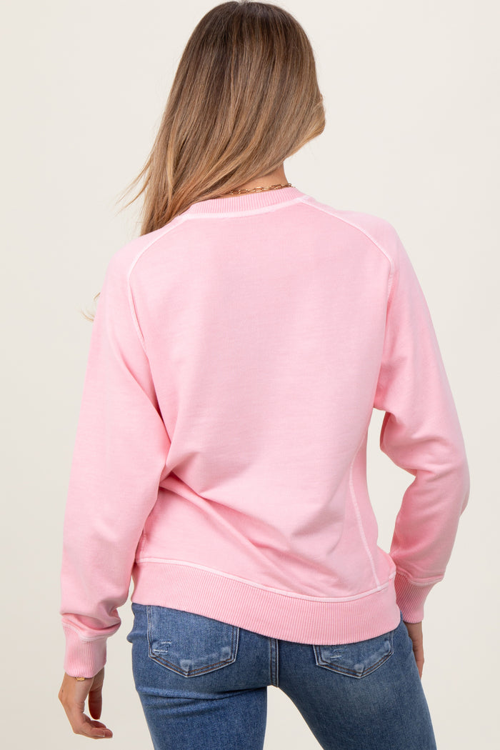 woman wearing a light pink maternity sweatshirt with a relaxed fit, seen from the back