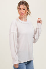 woman wearing a light beige oversized ribbed sweater with balloon sleeves and a relaxed fit