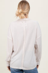 woman wearing a light beige oversized long sleeve top with a back seam detail and relaxed fit