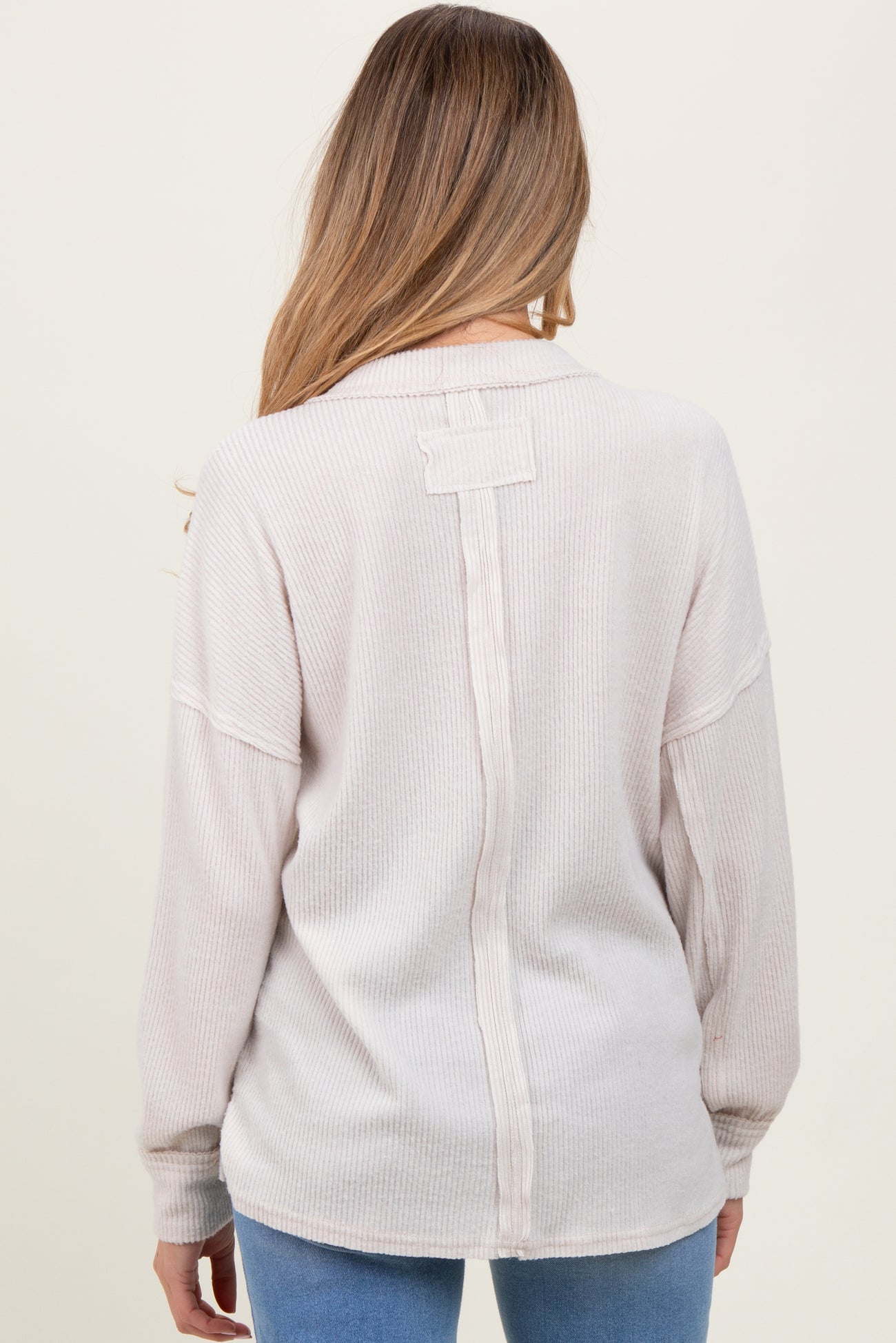 woman wearing a light pink ribbed maternity top with a button detail on the back