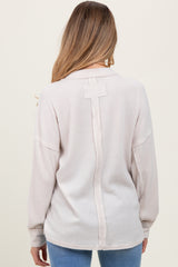 woman wearing a light pink ribbed maternity top with a button detail on the back