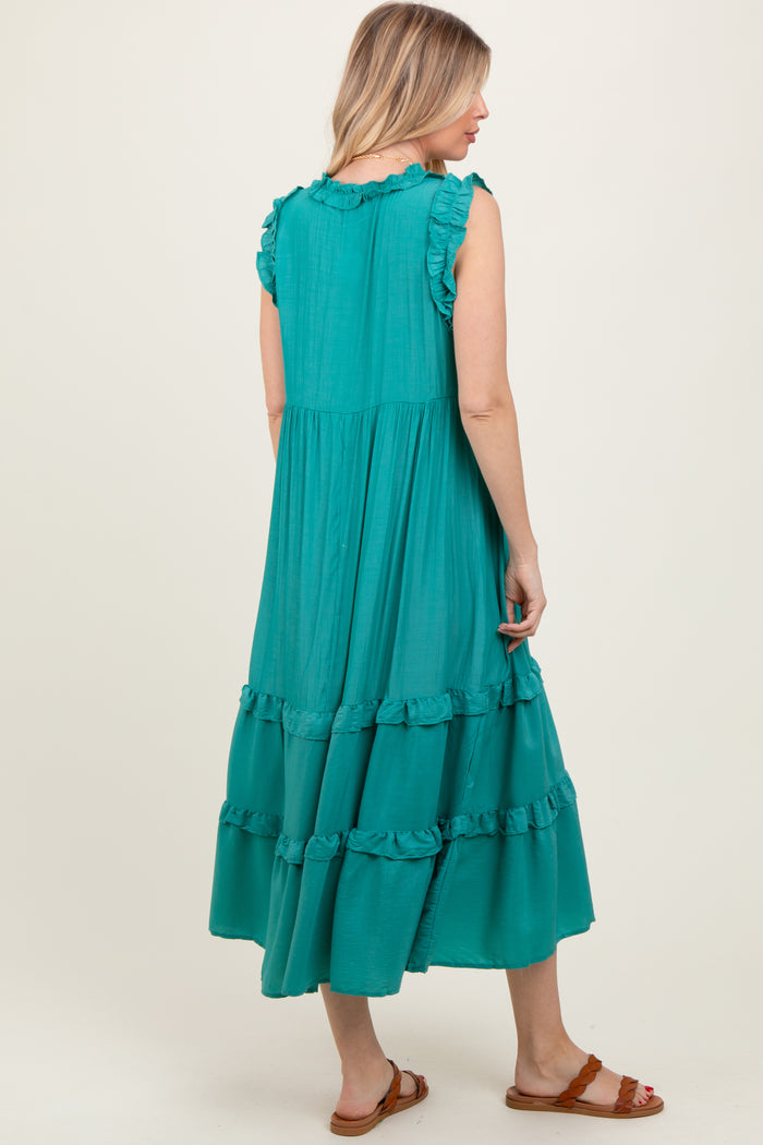woman wearing a teal tiered maxi dress with ruffled sleeves and hem, styled with brown sandals