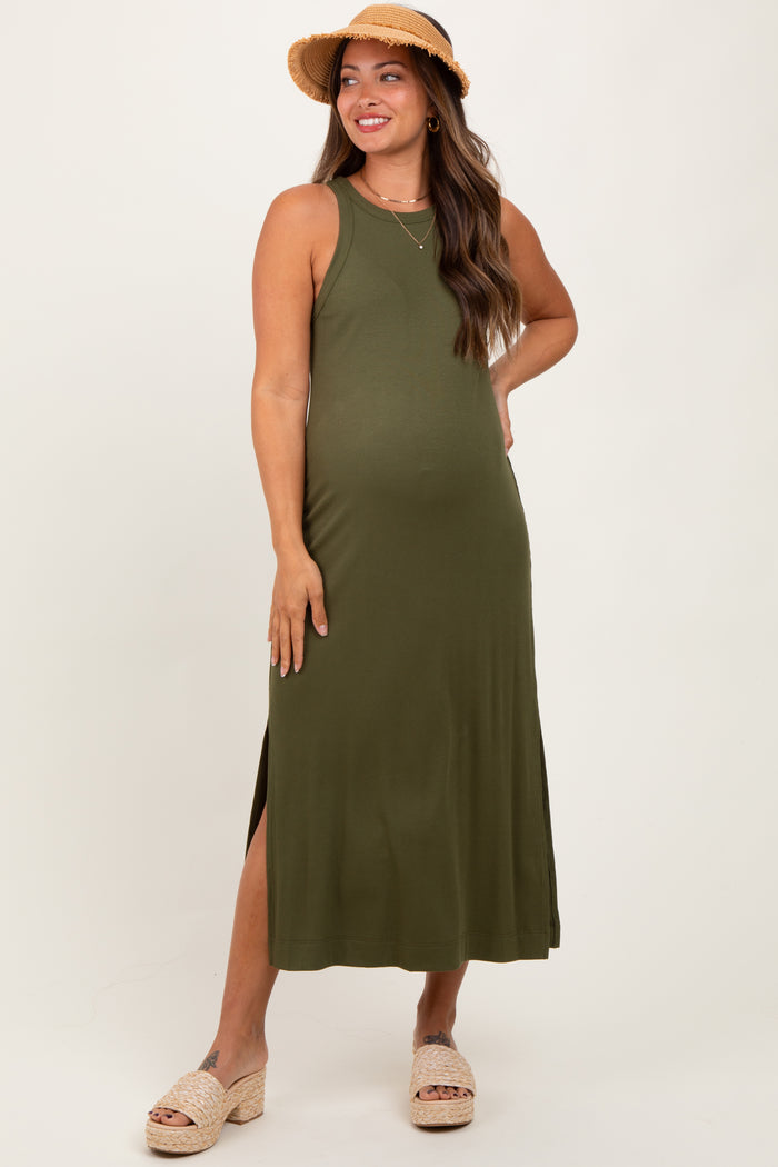 woman wearing an olive green maternity maxi dress with side slits and a straw hat, showing her baby bump