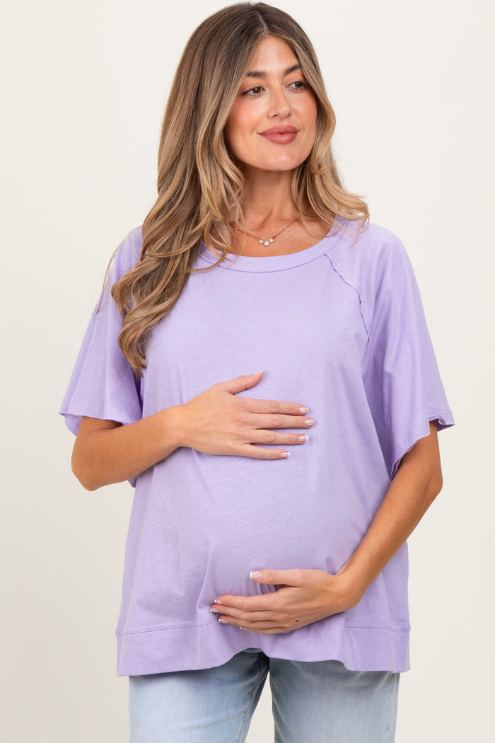 woman wearing a light purple maternity top and holding her baby bump