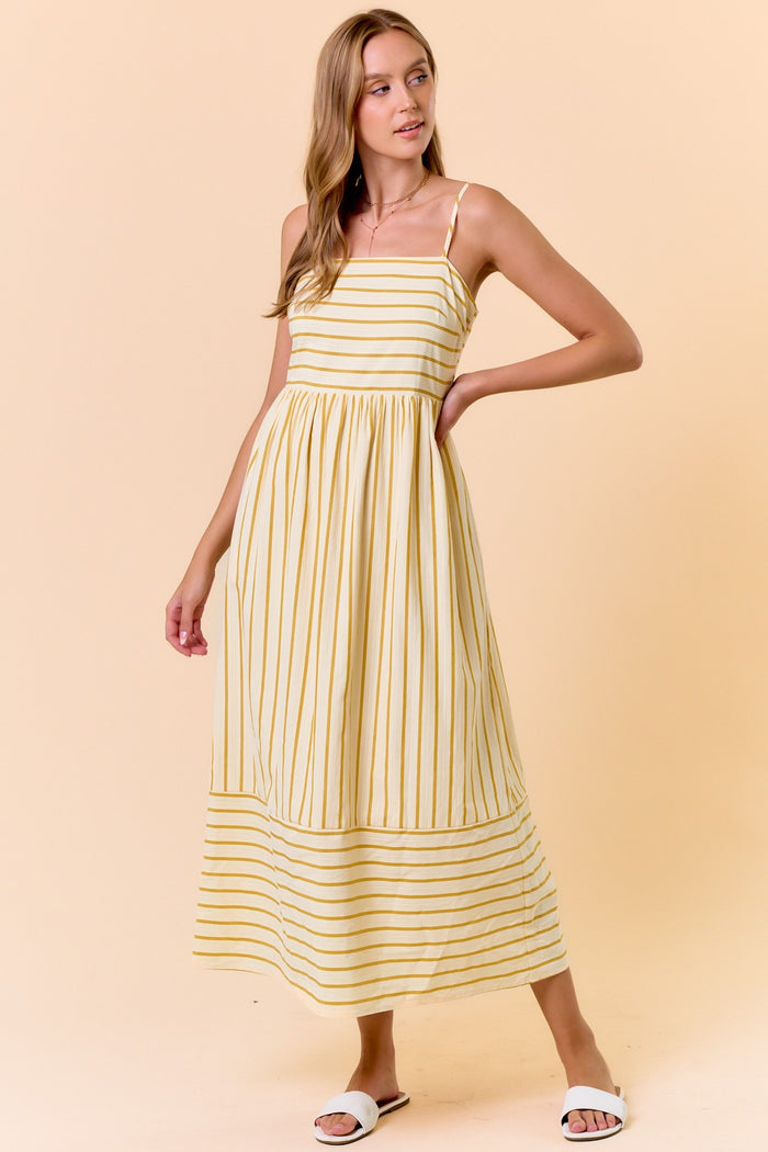 woman wearing a yellow and white striped maxi dress with thin straps and a gathered waist