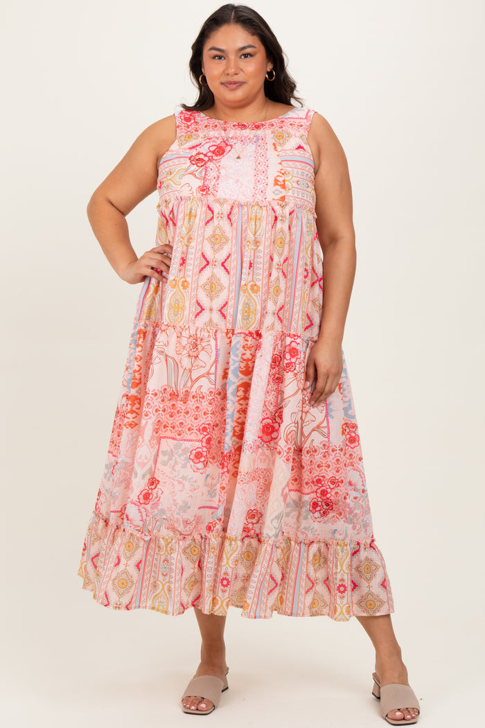 woman wearing a colorful plus size maxi dress with a tiered design and floral patterns, standing with one hand on her hip