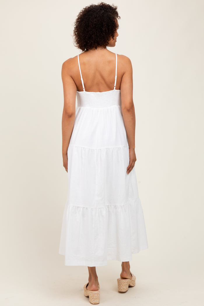 woman wearing a white maxi dress with a smocked bodice and tiered skirt, seen from the back