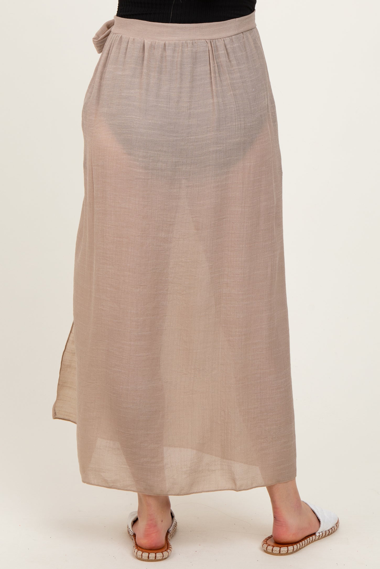 woman wearing a beige maternity maxi skirt with a tie detail at the waist and a flowing, lightweight design