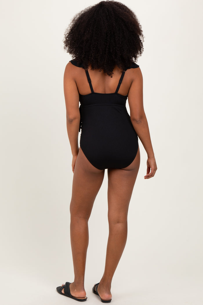 woman wearing a black ribbed one-piece swimsuit with adjustable straps, viewed from the back