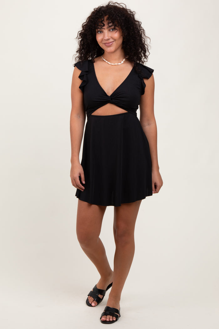 woman wearing a black short dress with ruffle sleeves and a cut-out design, paired with black sandals