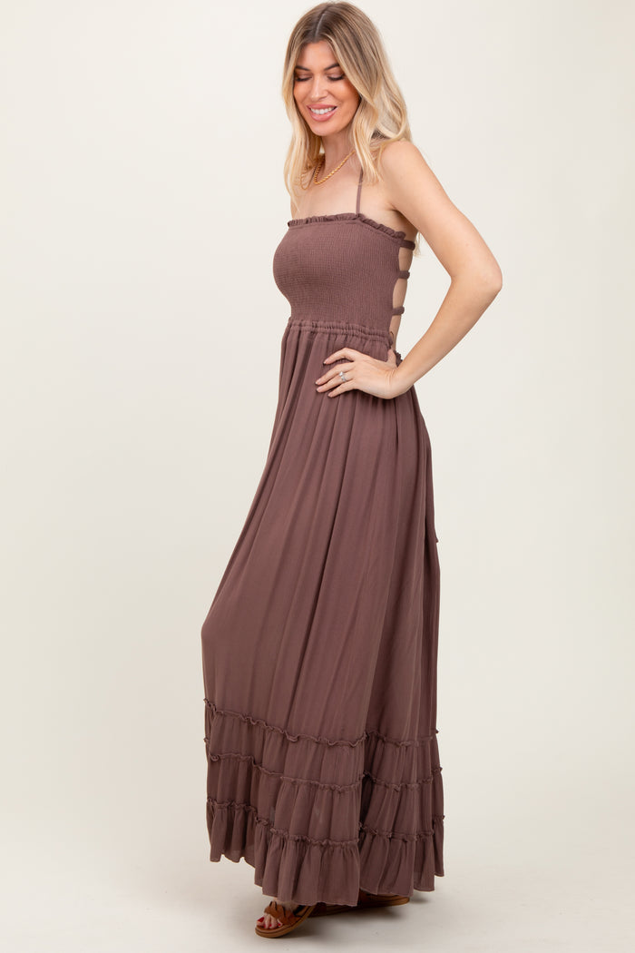 woman wearing a brown maxi dress with a smocked bodice and tiered ruffle hem, styled with thin straps