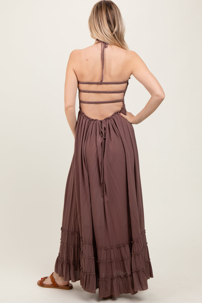 woman wearing a dusty mauve maxi dress with a halter neck and ruffled hem, showcasing an open back design