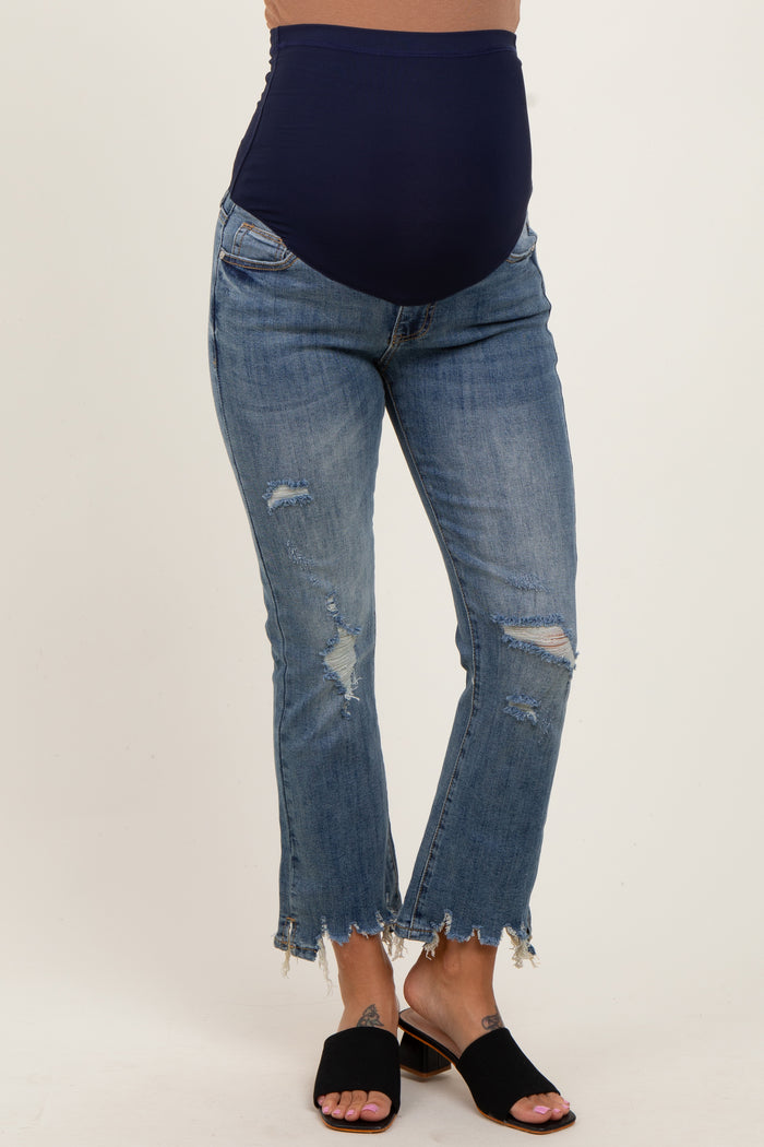 woman wearing blue distressed maternity jeans with a navy belly panel and frayed hem, showing her baby bump