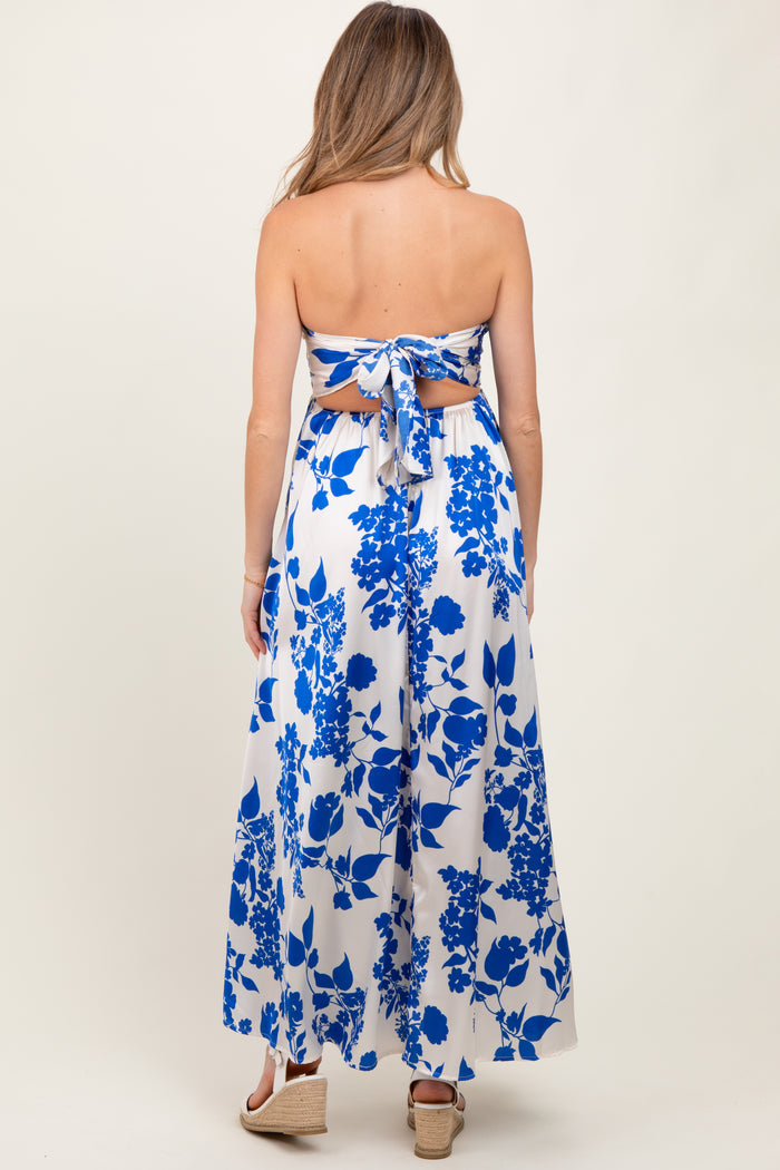 woman wearing a blue and white floral strapless maternity maxi dress with a tied back detail and a flowing silhouette