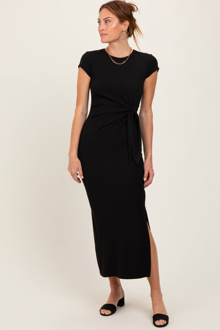 woman wearing a black cap sleeve maxi dress with a knotted waist detail and side slit