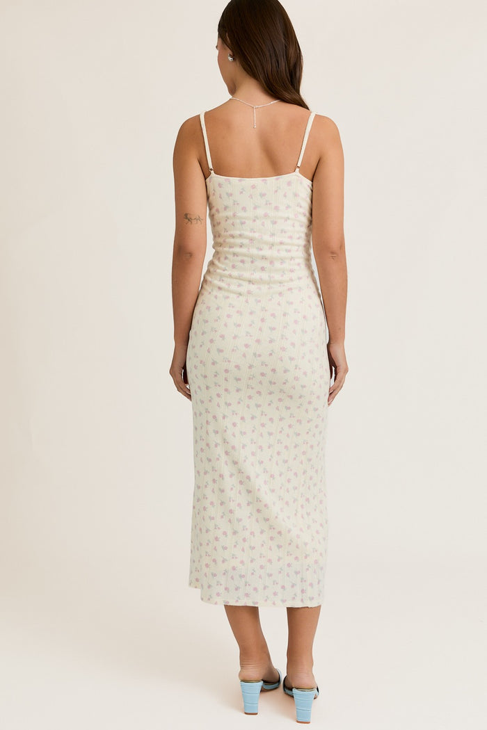 woman wearing a light green spaghetti strap maxi dress with a floral print, seen from the back