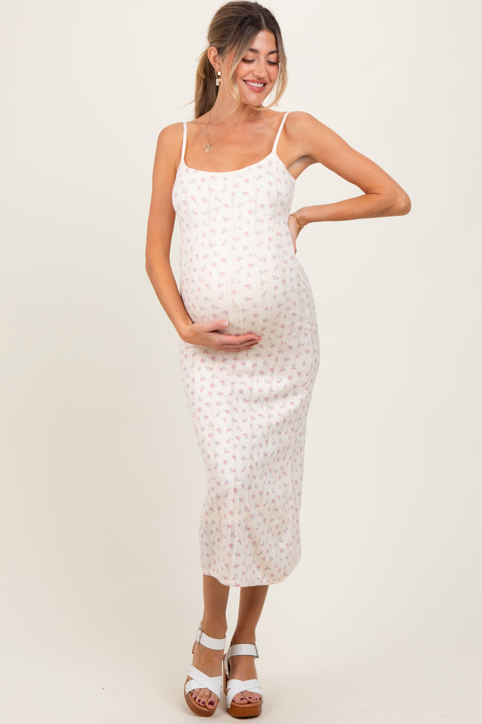 woman wearing a floral print maternity dress with thin straps, holding her baby bump