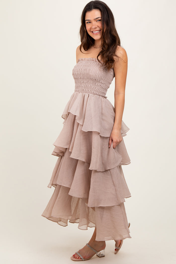 woman wearing a strapless taupe tiered maxi dress with a smocked bodice and ruffled layers