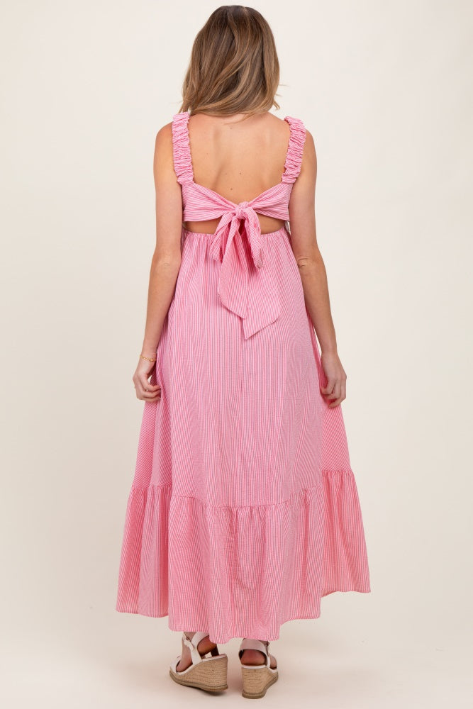 woman wearing a pink and white striped maternity maxi dress with a ruffled back and tie detail