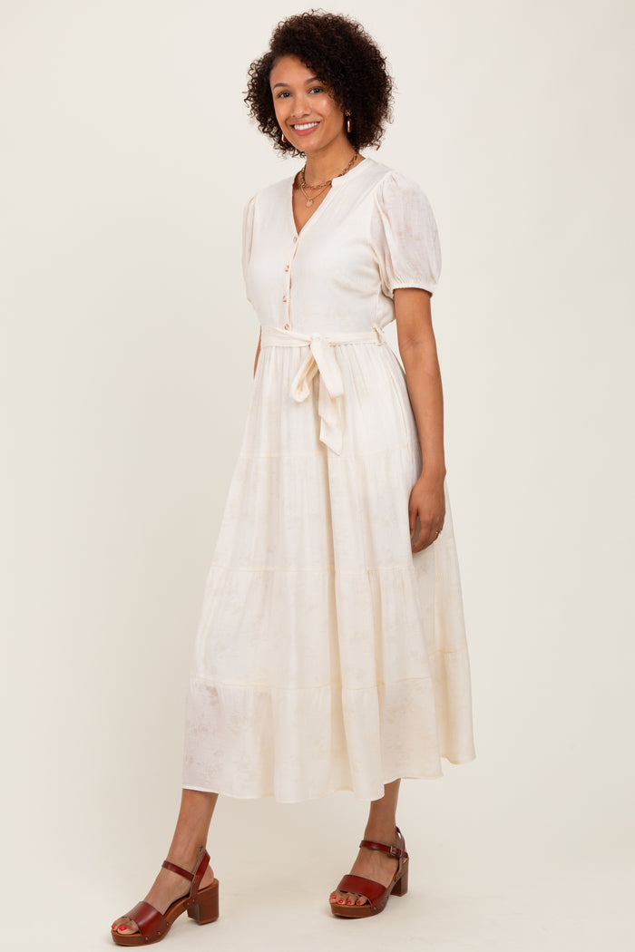 woman wearing a cream-colored button-up midi dress with short puff sleeves and a tie waist detail