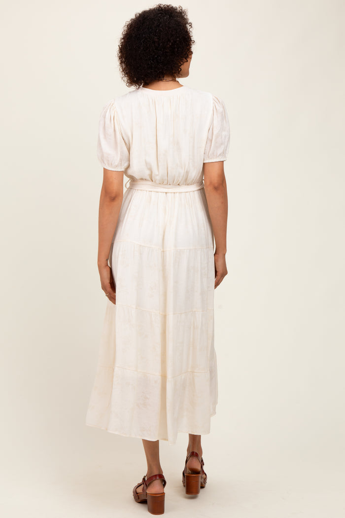 woman wearing a white tiered midi dress with puff sleeves and a belted waist, viewed from the back