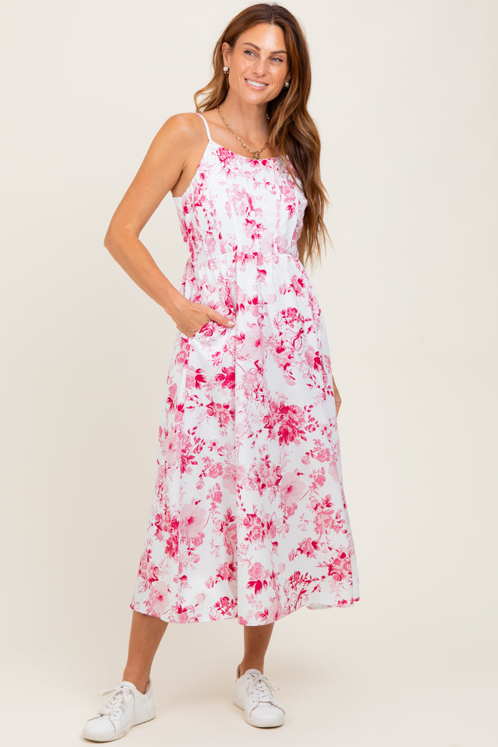 woman wearing a white floral midi dress with pink patterns and pockets, paired with white sneakers