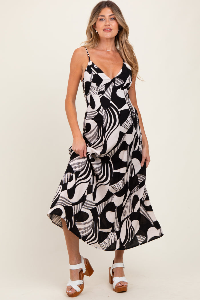 woman wearing a black and white abstract print maternity dress with a v-neck and spaghetti straps