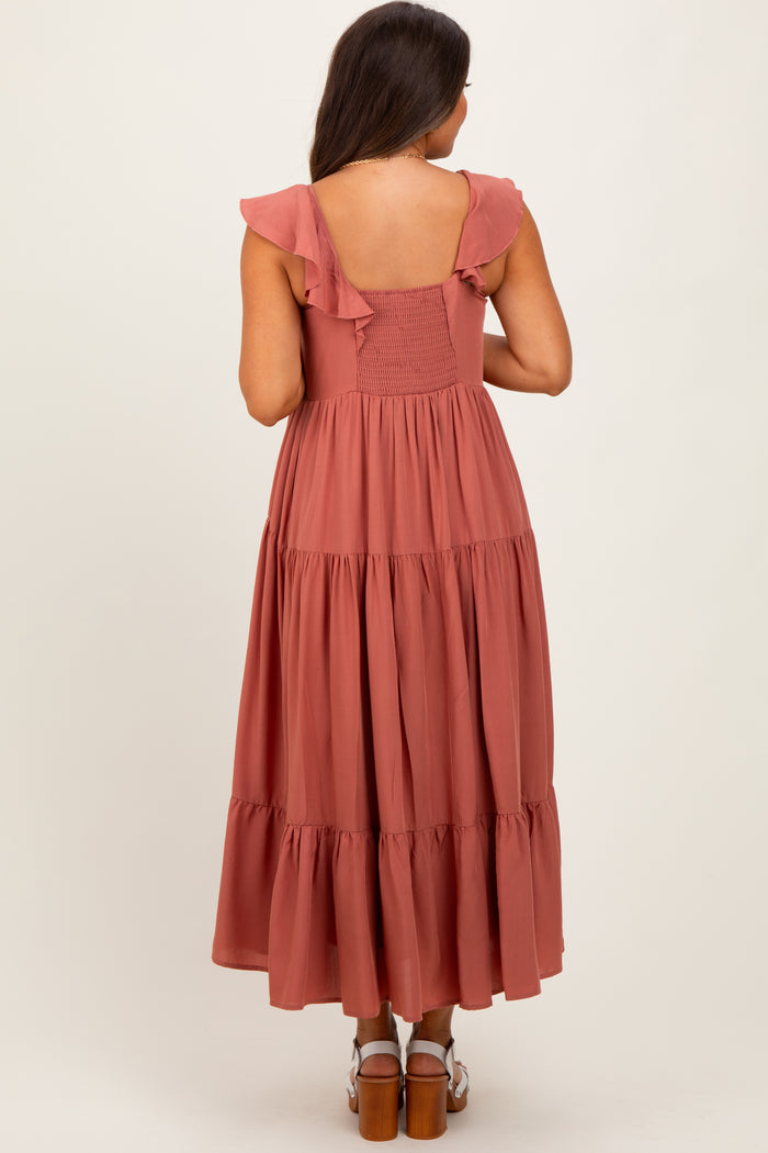 woman wearing a dusty rose maternity maxi dress with ruffle straps and a tiered skirt, showing her baby bump from the back
