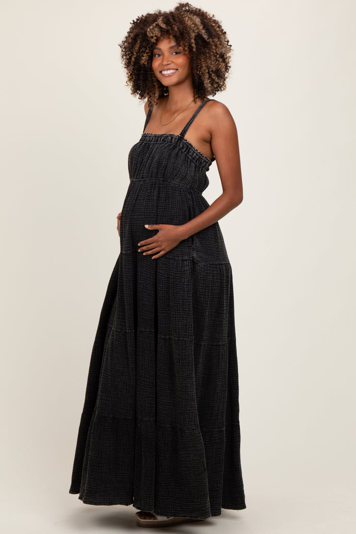 woman wearing a black tiered maxi maternity dress and gently cradling her baby bump