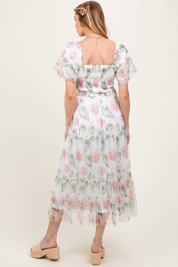 woman wearing a floral maternity maxi dress with puff sleeves and a smocked bodice, showing a baby bump from the back