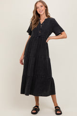 woman wearing a black tiered midi dress with short sleeves and buttons at the neckline