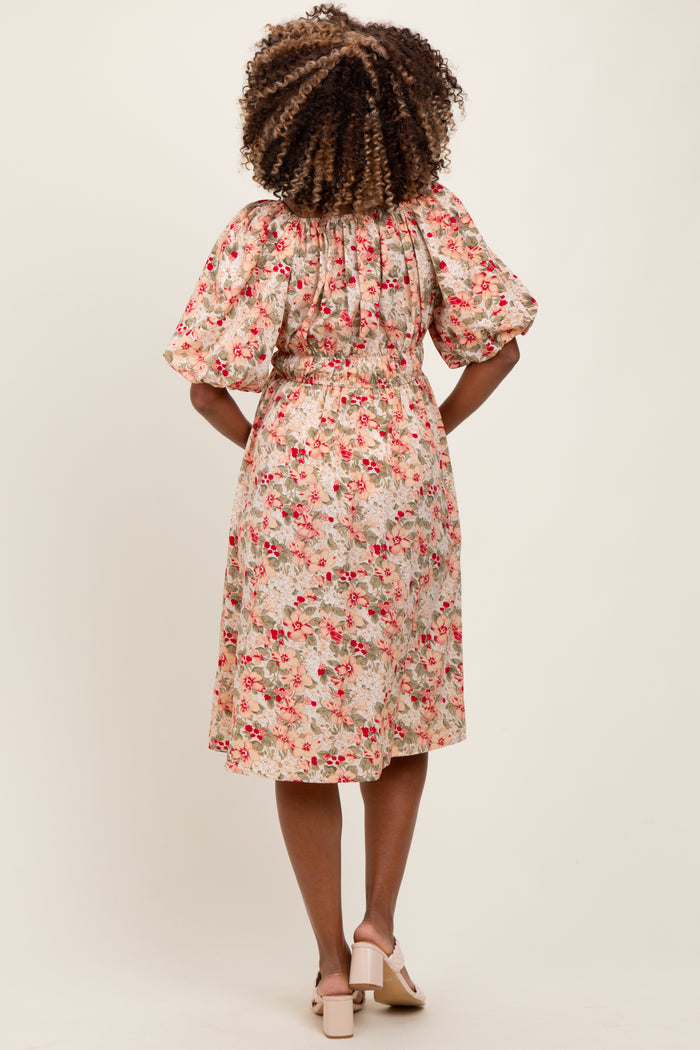 woman wearing a floral print maternity dress with puff sleeves and a cinched waist, showing off her baby bump from the back