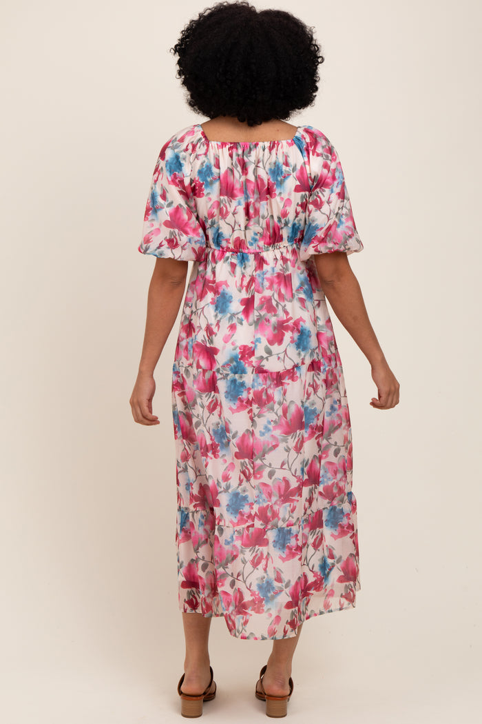 woman wearing a floral maxi dress with pink and blue flowers, featuring puff sleeves and a smocked waist, shown from the back