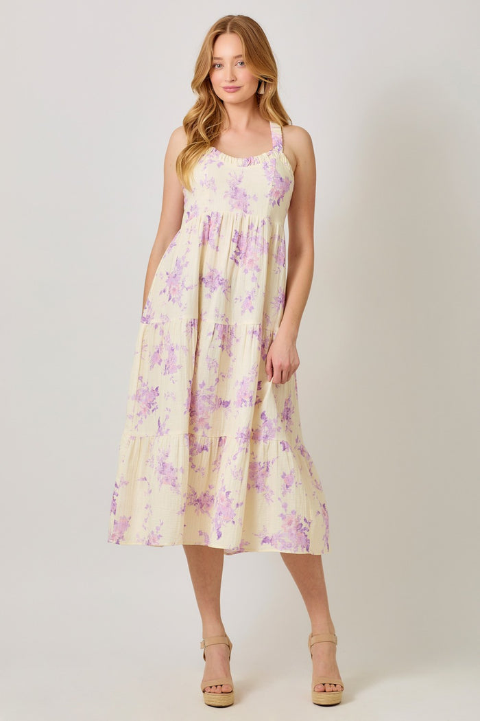 woman wearing a flowy yellow maxi dress with purple floral print and thin straps