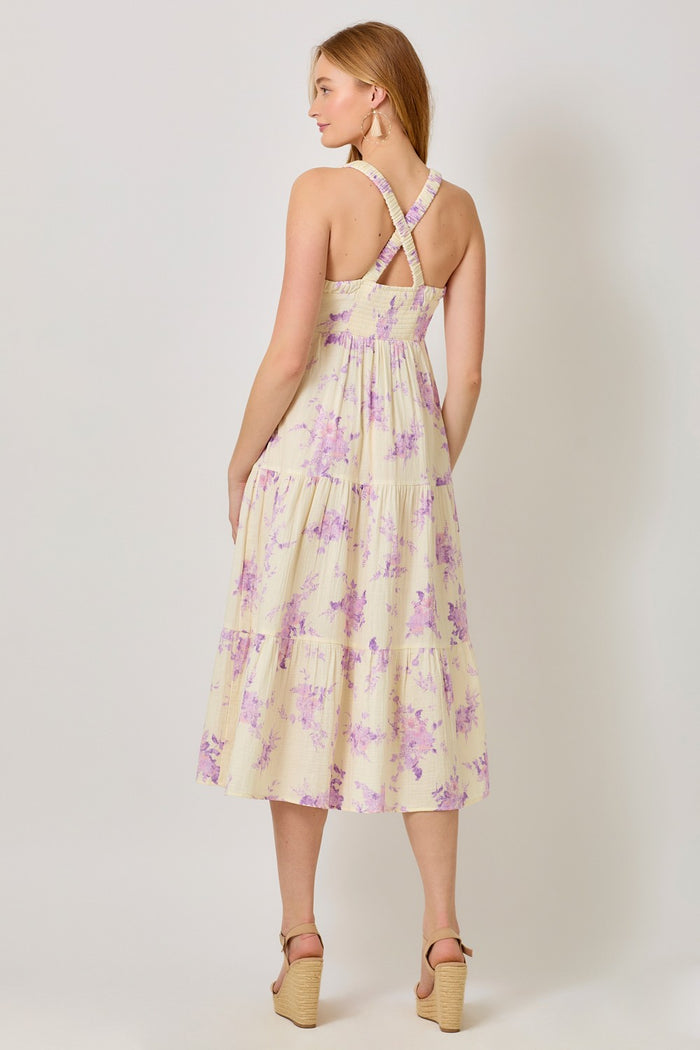 woman wearing a yellow floral midi dress with cross-back straps and tiered skirt, viewed from the back