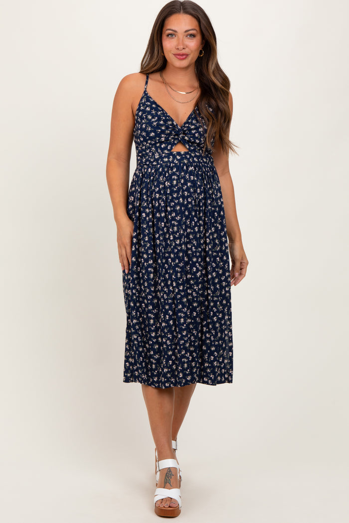 woman wearing a navy floral maternity dress with a front knot detail and a flowy skirt, showcasing her baby bump