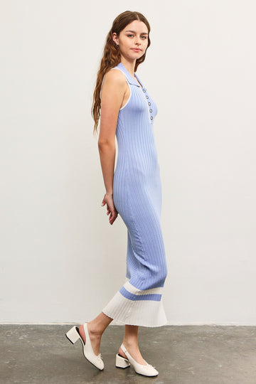 woman wearing a light blue ribbed knit midi dress with buttons and a white hem, standing sideways on a gray floor
