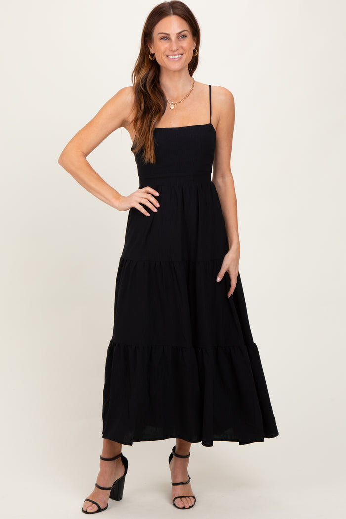 woman wearing a black sleeveless maxi dress with tiered ruffle details and a fitted bodice