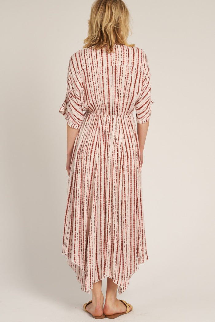 woman wearing a white and red striped maxi dress with a high-low hem and tied waist, shown from the back