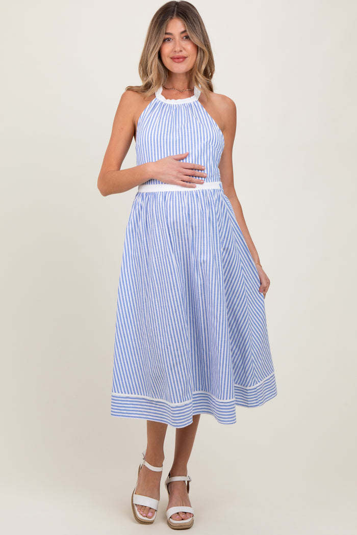 woman wearing a blue and white striped maternity dress with a halter neck, holding her baby bump