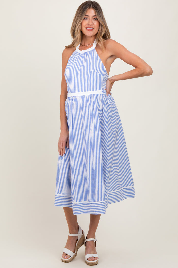 woman wearing a blue and white striped maternity dress with halter neck and flared skirt, posing with one hand on her hip