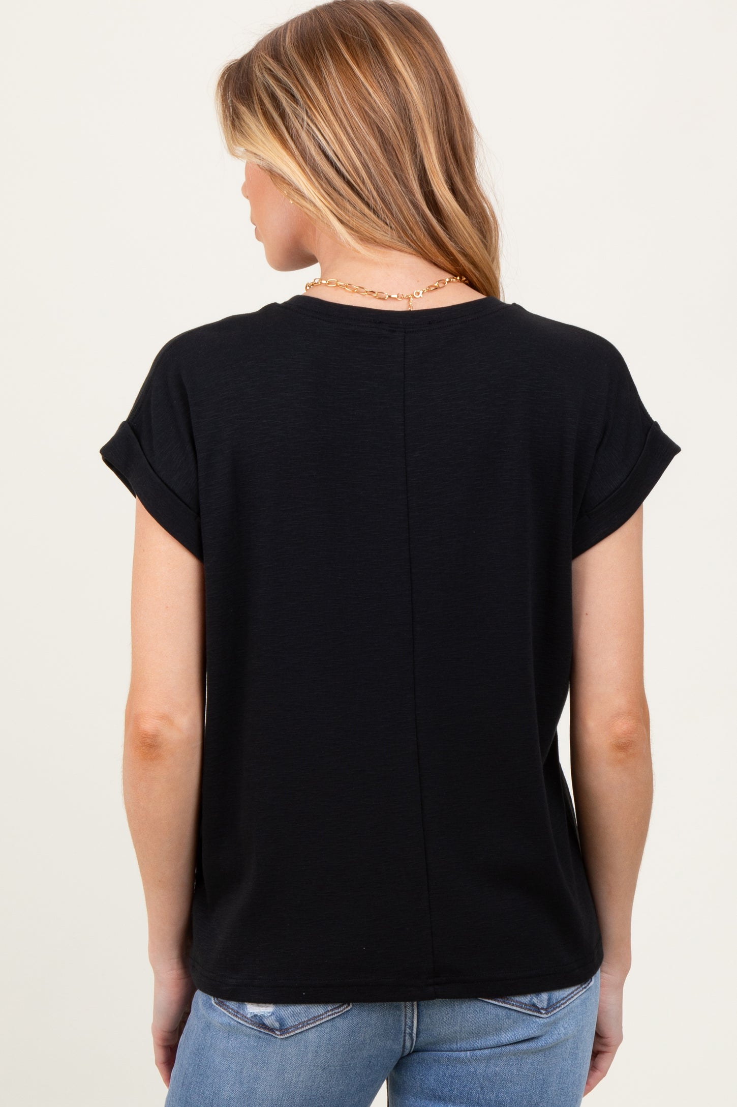 woman wearing a black maternity top with rolled sleeves and a relaxed fit, viewed from the back