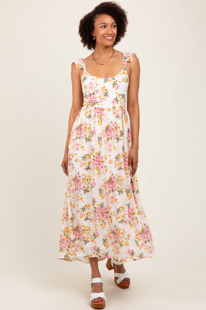 woman wearing a floral maxi dress with ruffled straps and a fitted waist, standing against a light background