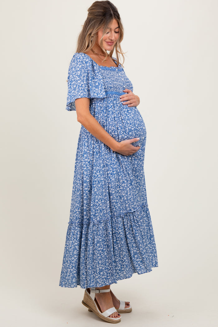 woman wearing a blue floral maternity maxi dress and holding her baby bump