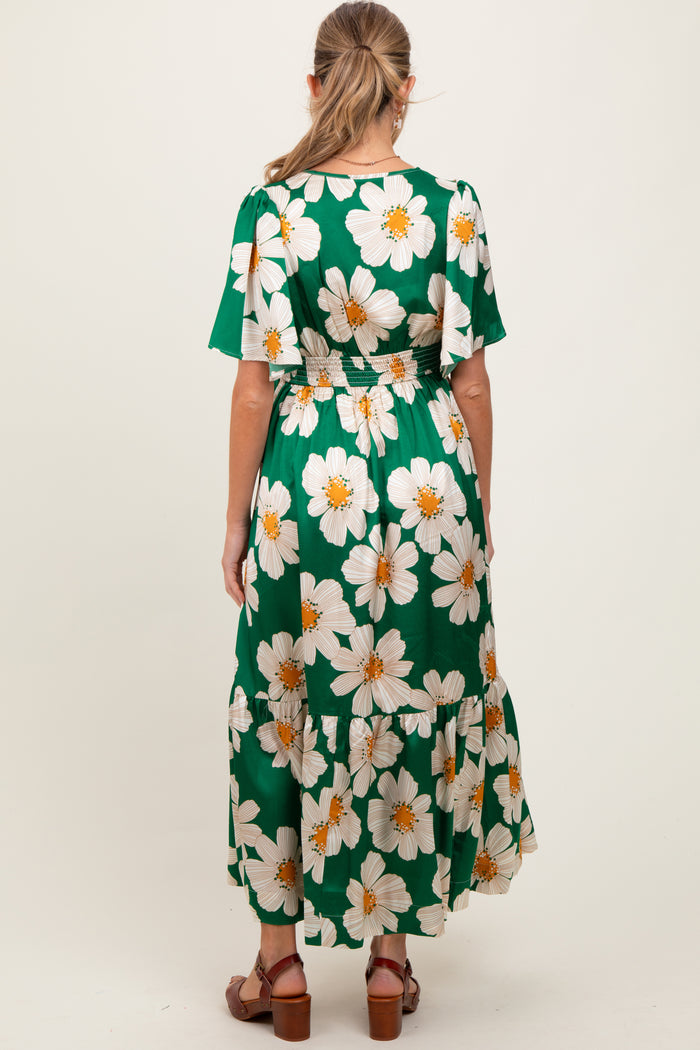 woman wearing a green floral maternity dress with puff sleeves and a tiered skirt, showing her back view