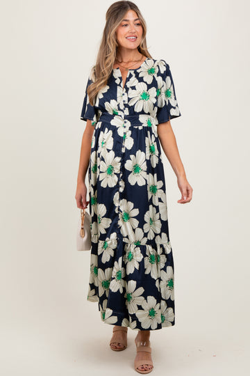 woman wearing a navy floral maternity maxi dress with short sleeves and a tiered skirt, holding a small bag
