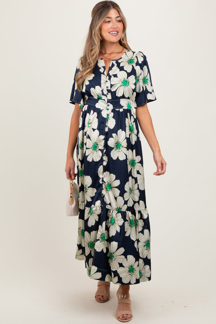 woman wearing a navy floral maternity maxi dress with short sleeves and a tiered skirt, holding a small bag
