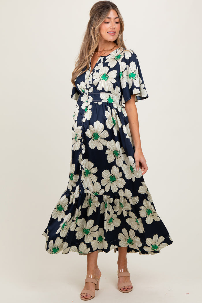 woman wearing a navy floral maternity dress with short sleeves and a tiered skirt, showcasing her baby bump