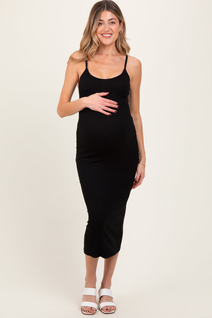 woman wearing a black ribbed maternity dress, showing her baby bump, standing in a relaxed pose